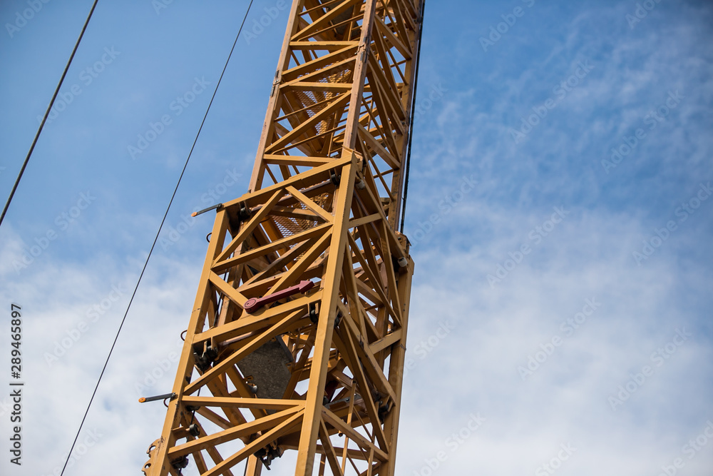 Construction site with cranes on sky background. Big yellow machinery construction crane tool of building industry for heavy lifting on blue sky background. Business engineering equipment modern Construction site with cranes on sky background. Big yellow machinery construction crane tool of building industry for heavy lifting on blue sky background. Business engineering equipment modern