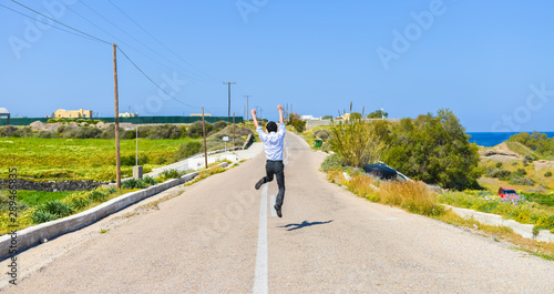 Back portrait of single young man jumping in the road