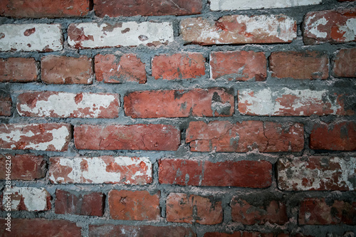 The wall of red dilapidated brick. The ruined brick wall close-up. Facade of a destroyed brick building. Pattern, texture, background.