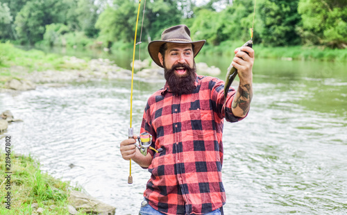 Fishing requires to be mindful and fully present in moment. Fisher fishing equipment. Rest and recreation. Fish on hook. Brutal man stand in river water. Man bearded fisher. Fisher masculine hobby