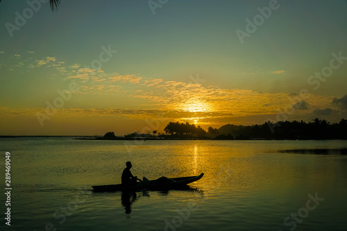 People are paddling boats in the middle of the beach with beautiful sunset background