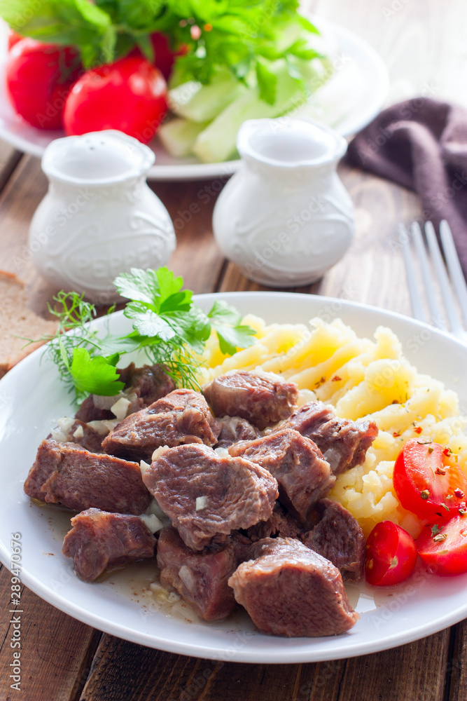 Beef stew with mashed potatoes on a white plate, selective focus