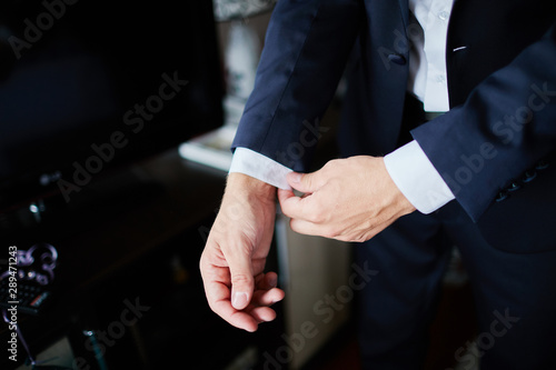 the groom straightens the wedding suit