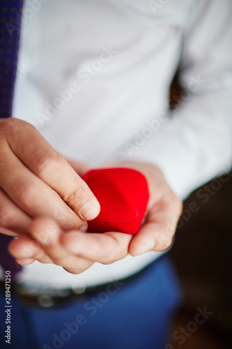 groom holds wedding rings in his hands