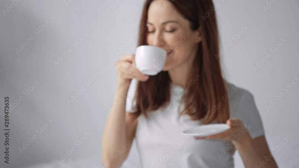 happy woman smelling and drinking coffee in bed happy woman smelling and drinking coffee in bed