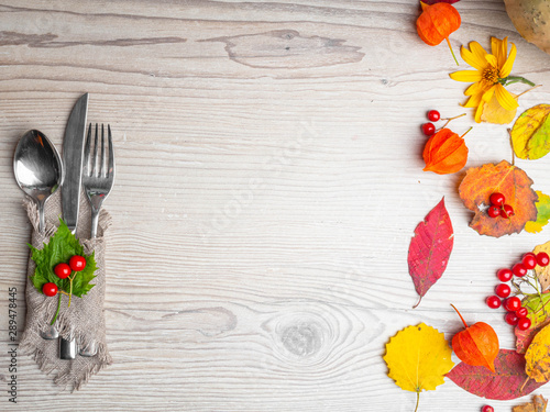 festive Thanksgiving autumn place setting with cutlery and arrangement of colorful leaf  red berries