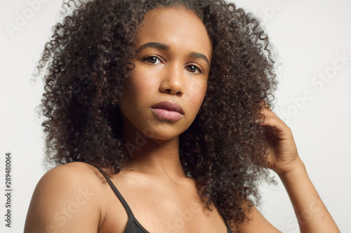 closeup portrait of young mixed race model with curly hair in studio with natural neutral makeup with big curly afro hair