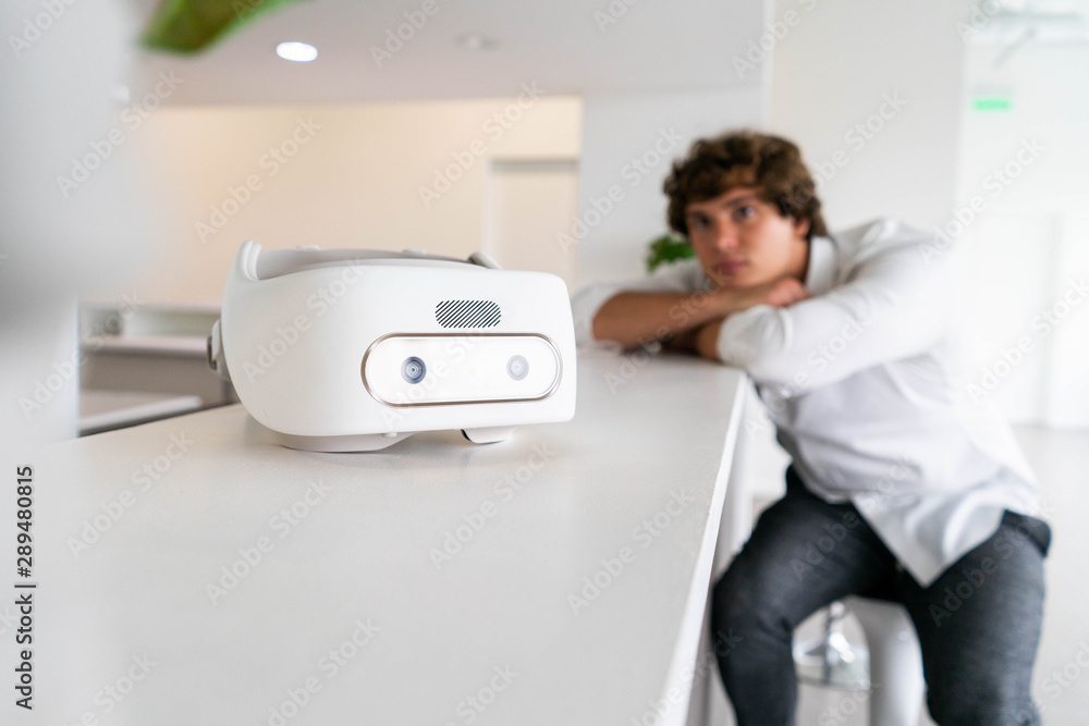 Man sitting near virtual reality goggles in modern contemporary bright co-working office. the VR experience. Man sitting near virtual reality goggles in modern contemporary bright co-working office. the VR experience.