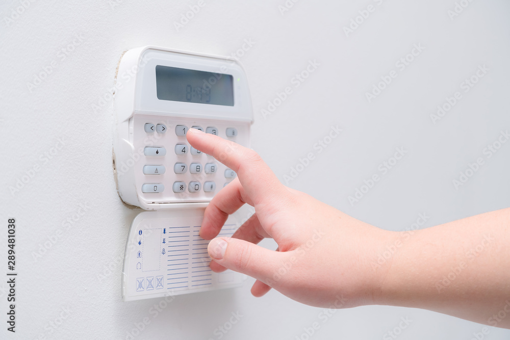 Woman hand entering alarm system password of an apartment, house of business office. Surveillance and protection console against rubbery and thief Woman hand entering alarm system password of an apartment, house of business office. Surveillance and protection console against rubbery and thief