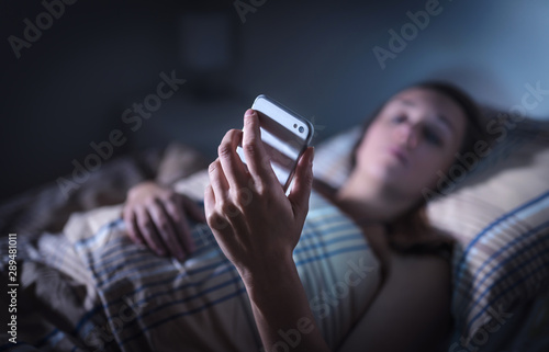 Canvastavla Sad upset woman looking at smartphone at night in bed