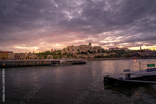 Buda castle with a river cruise passing by on the Danube with dramatic sunset sky © tamas