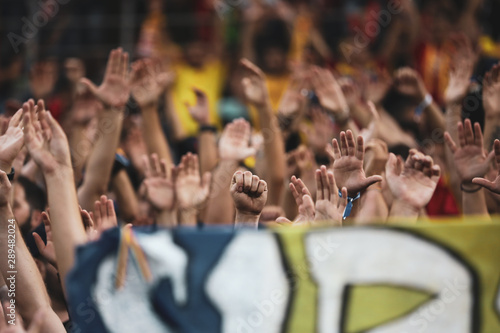 Details with a fist and hands of soccer fans during a game