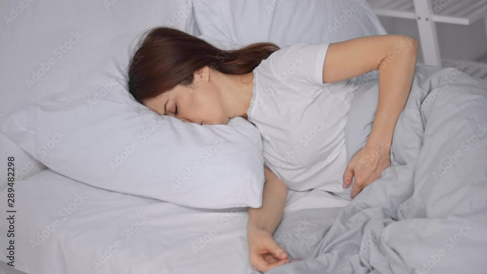 woman lying in bed and suffering from abdominal pain woman lying in bed and suffering from abdominal pain