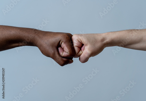 Fist of different skin colors giving fist bump. Conceptual image of race tolerance and stop racism photo