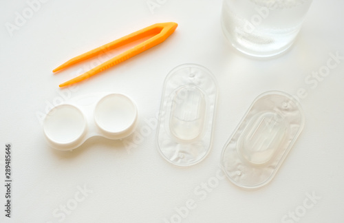 Accessories for use of contact lenses: case, tweezers, blister pack and solution on white background. Safe vision correction. View from above.
