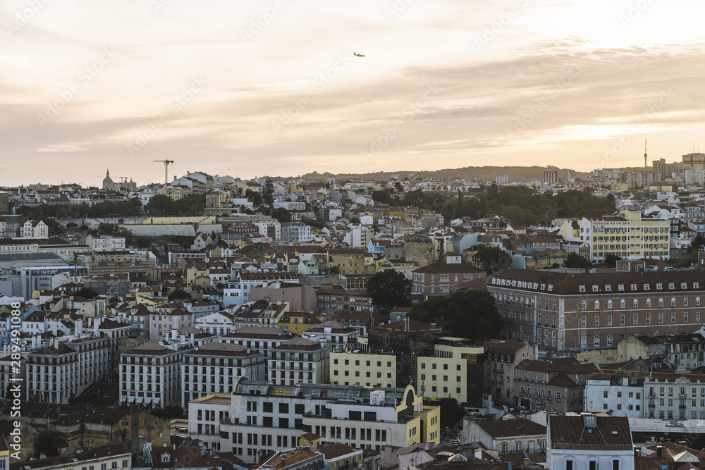 airplane flying over Lisbon at sunset