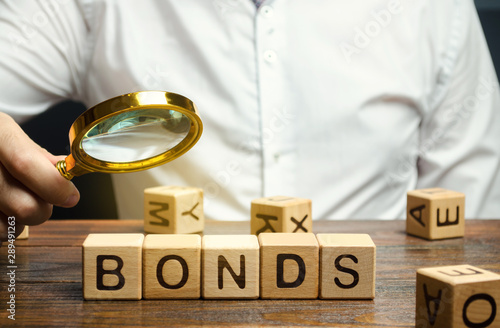 Wooden blocks with the word Bonds and businessman. A bond is a security that indicates that the investor has provided a loan to the issuer. Equivalent loan. Unsecured and secured bonds. photo