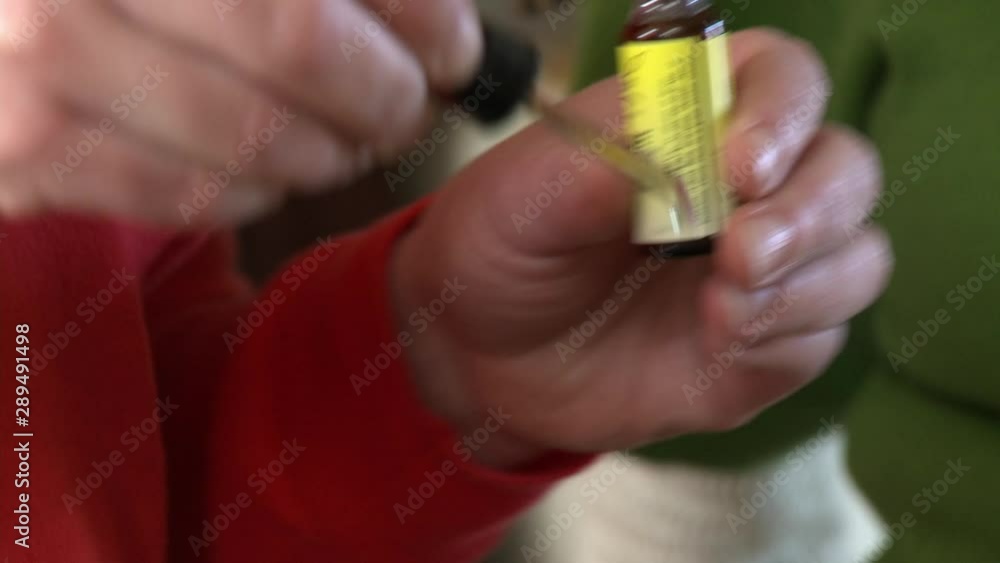 A person using an eyedropper to carefully drip chemicals into a pot to dye fabric