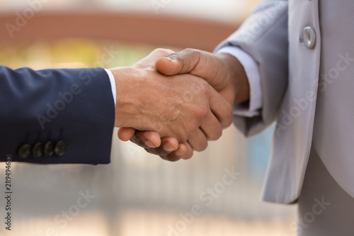 Closeup of business leaders handshake. Business people in office suits shaking hands with each other. Formal communication concept