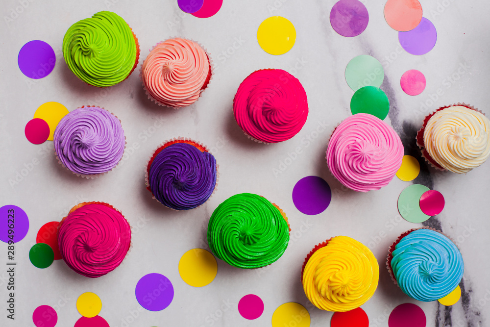 Colourfull rainbow cupcakes with confetti flat lay Colourfull rainbow cupcakes with confetti flat lay