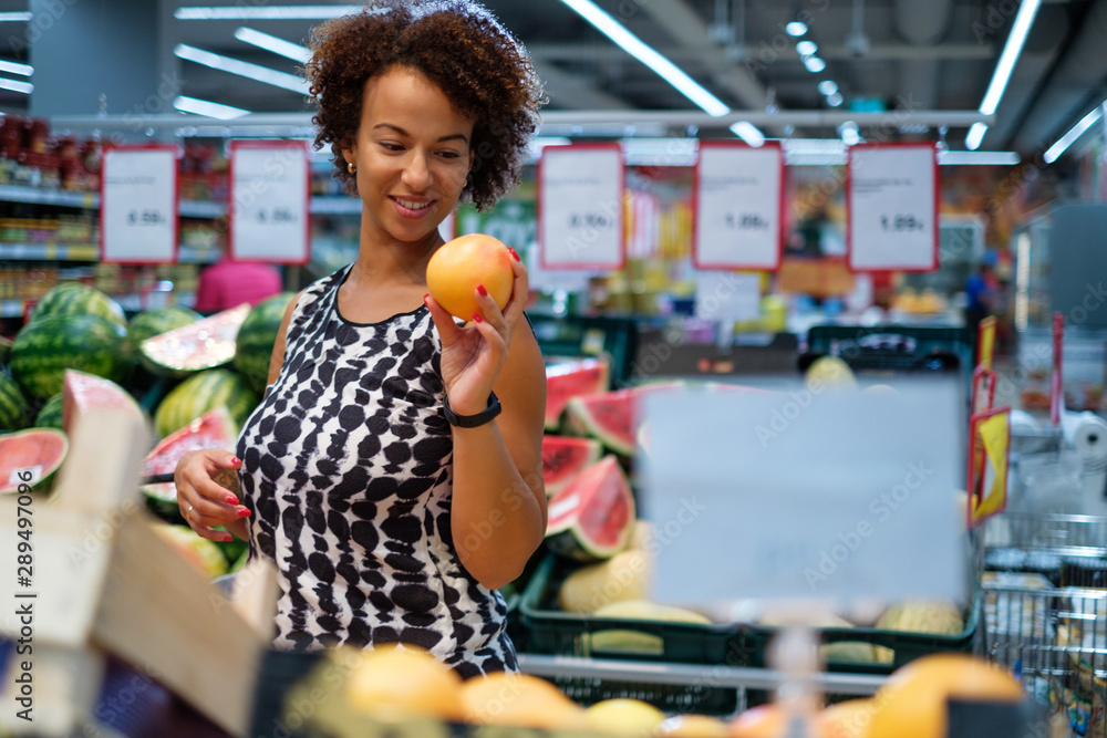 Fototapeta premium Pretty black woman choosing fruits in a grocery store
