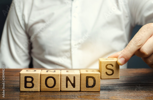 Businessman puts wooden blocks with the word Bonds. A bond is a security that indicates that the investor has provided a loan to the issuer. Equivalent loan. Unsecured and secured bonds. photo