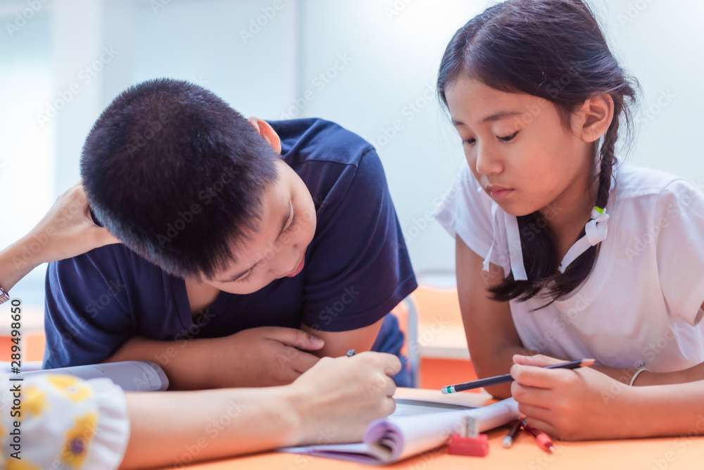 Asian elementary school boy and girl are studying and having fun in the classroom with female teachers. Asian elementary school boy and girl are studying and having fun in the classroom with female teachers.