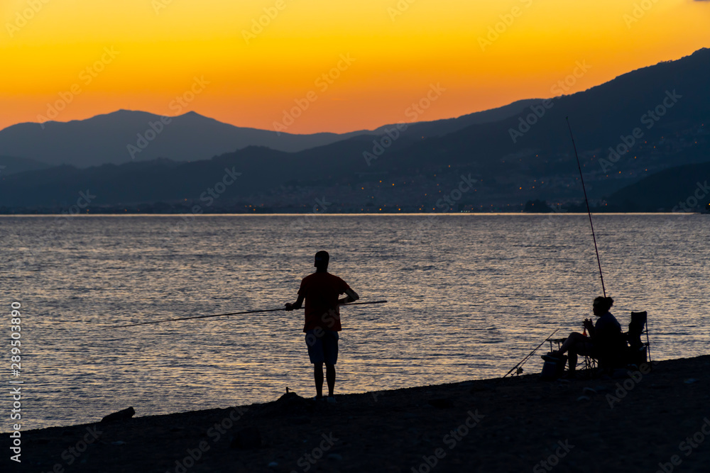 Fishing couple on beach at he end of day