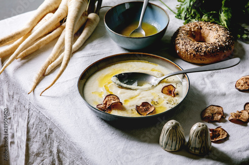 Fotografija Parsnip cream soup in ceramic bowl with butter sauce, sun dried pears, bundle of
