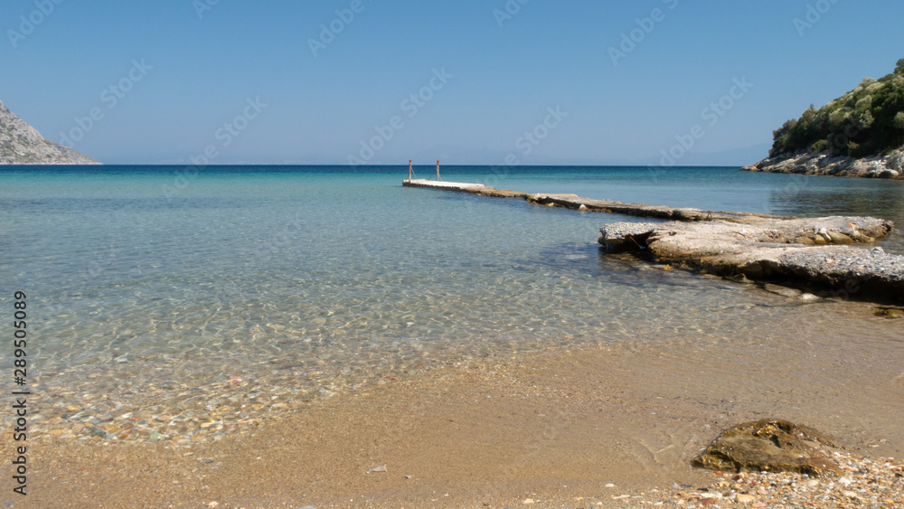 Perspective view of a wooden pier on the seashore with clear blue sea