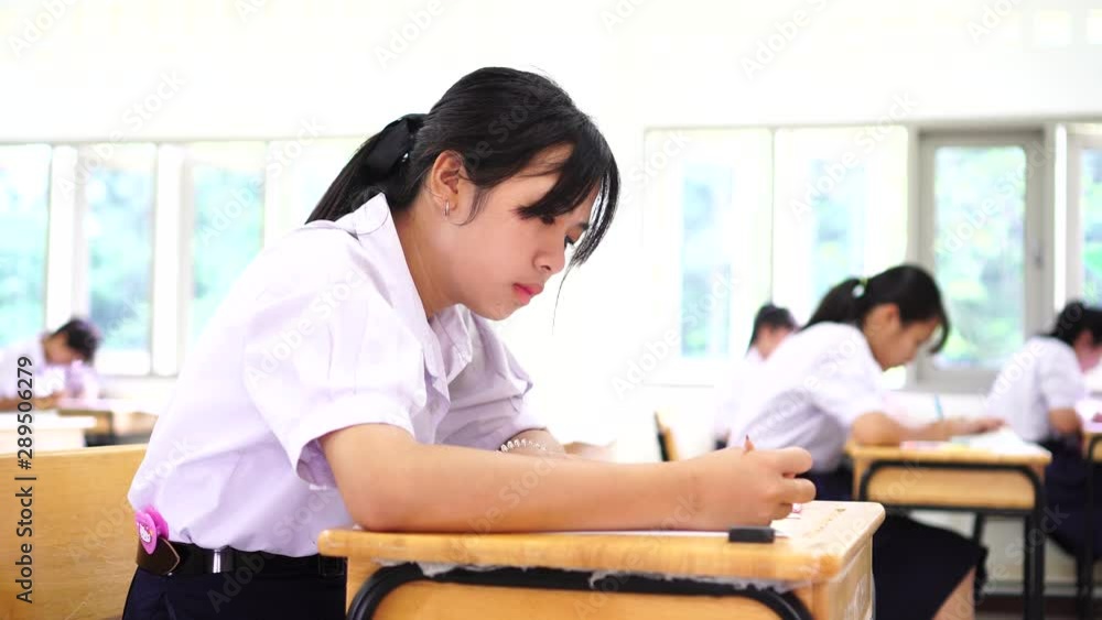 Exam assessment concept, Asian students young girls in college or high school having test exams for taking writing examination in school rows chairs at classroom with uniform educational of Thailand. Exam assessment concept, Asian students young girls in college or high school having test exams for taking writing examination in school rows chairs at classroom with uniform educational of Thailand.
