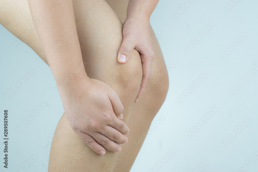 Closeup young woman massaging her painful knee. Healthcare and medical concept. Closeup young woman massaging her painful knee. Healthcare and medical concept.