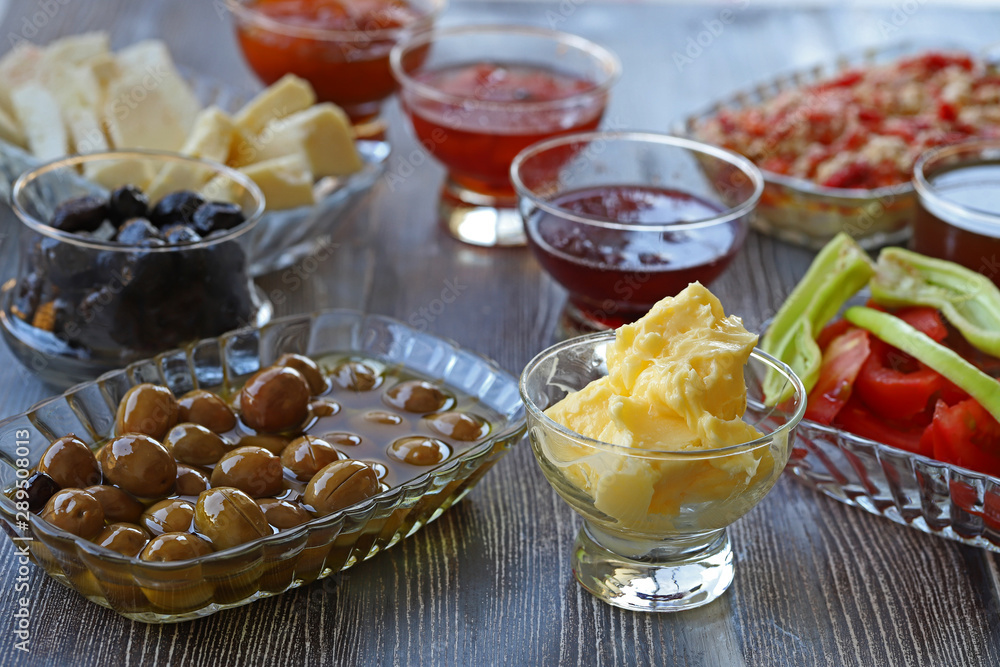 Breakfast with cheese, tomatoes, olives, butter and jam on wooden table. Breakfast with cheese, tomatoes, olives, butter and jam on wooden table.
