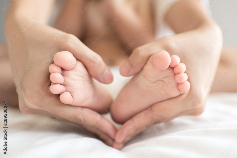 Mother's hand made into a heart shape, embracing the child's feet. Mother's hand made into a heart shape, embracing the child's feet.