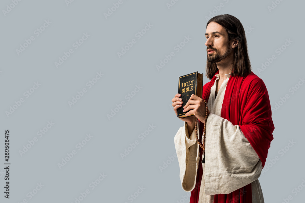 handsome bearded man holding holy bible isolated on grey handsome bearded man holding holy bible isolated on grey