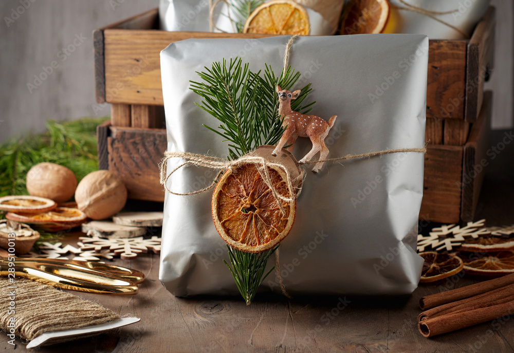 Packaging christmas present handmade gift boxes decorated with silver paper with dried orange slices