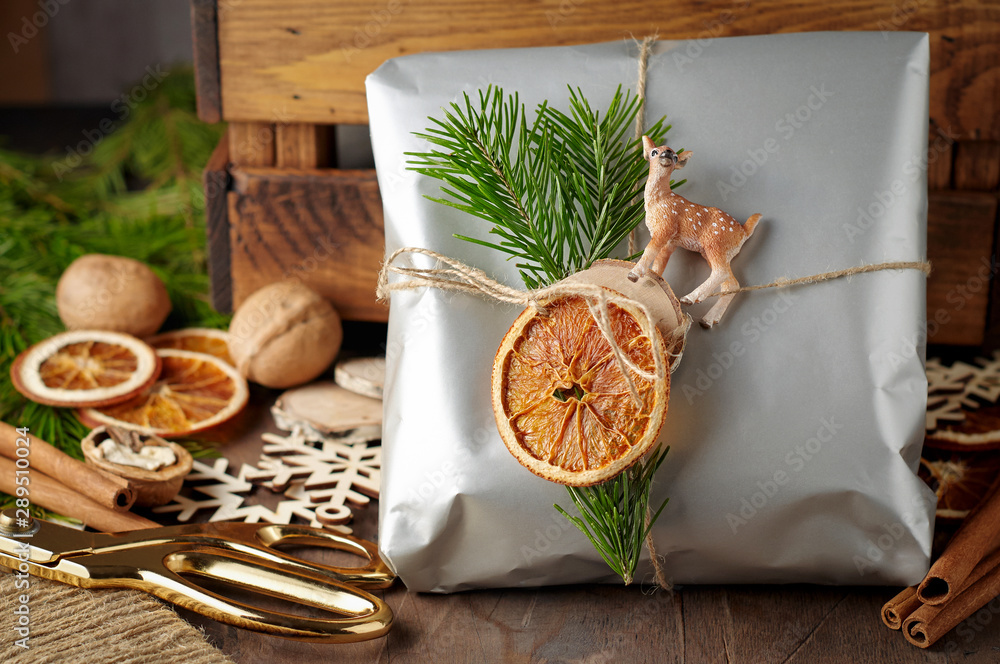 Packaging christmas present handmade gift boxes decorated with silver paper with dried orange slices