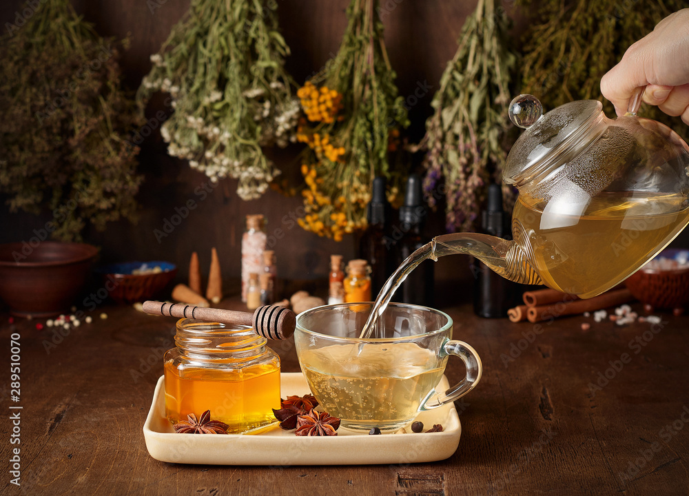 Cup of hot tea with honey, spices and drying medical herbs for use in alternative medicine