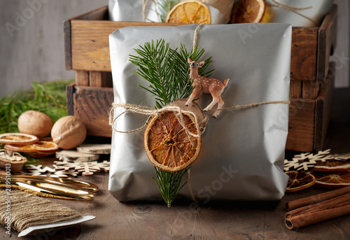 Packaging christmas present handmade gift boxes decorated with silver paper with dried orange slices