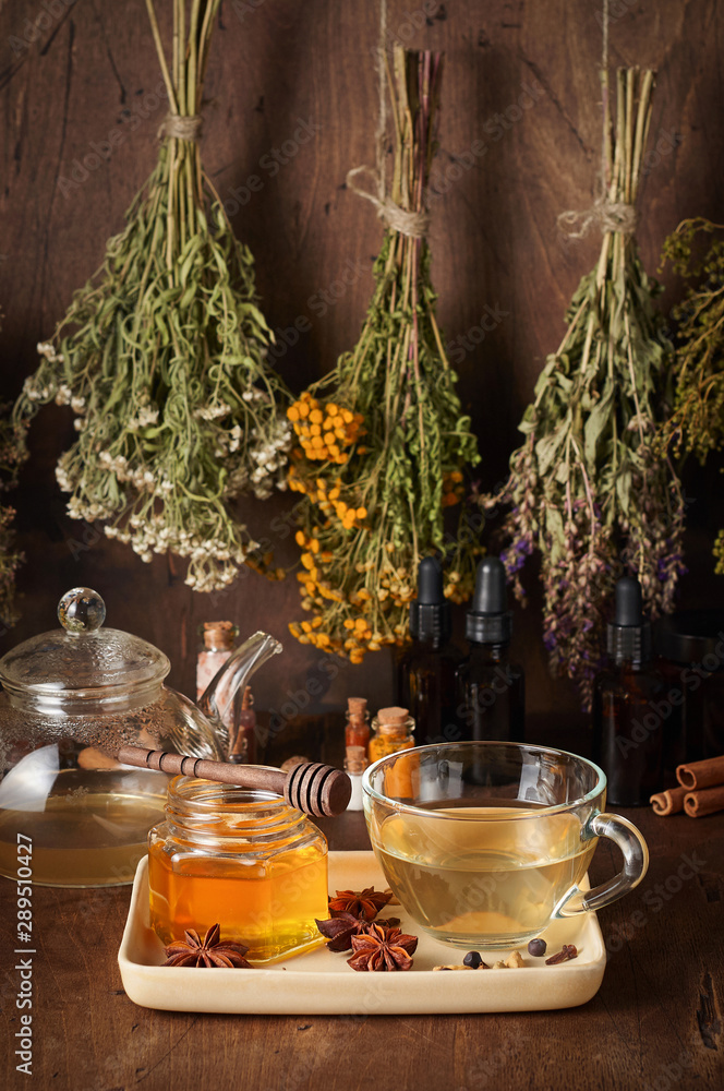 Cup of hot tea with honey, spices and drying medical herbs for use in alternative medicine