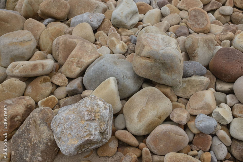 CLOSE UP BEACH STONES ROUNDED BY EROSION