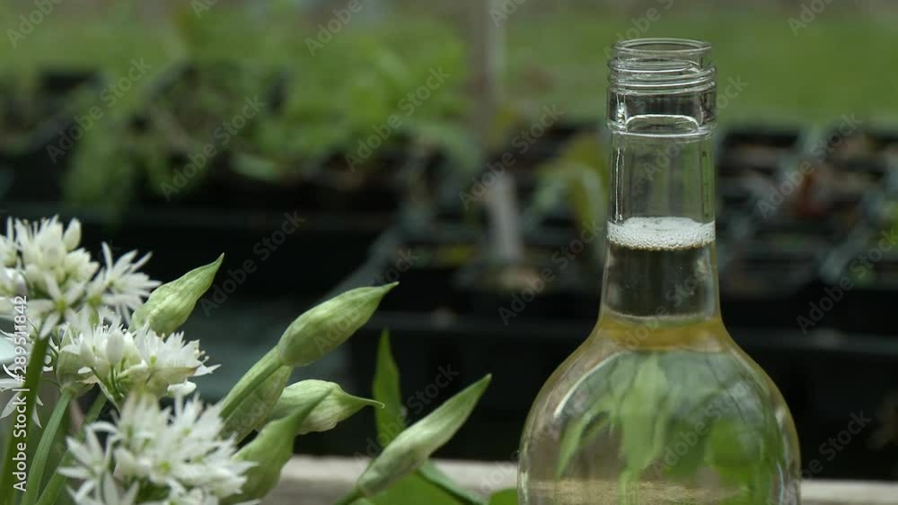 The top of an open wine bottle next to white flowers outside The top of an open wine bottle next to white flowers outside