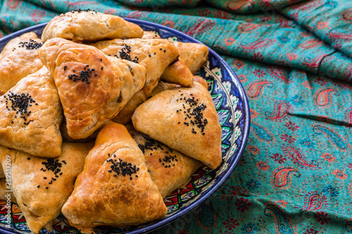 Uzbek Samsa or Sambousak in national plate. Samsa or Sambousak an oriental meal to be stuffed with minced meat, cheese or vegetables. The national dish of Uzbekistan and Central Asia.