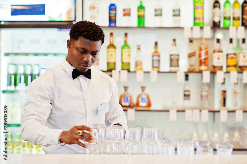African american bartender wear on bow tie cleaning glasses at bar. African american bartender wear on bow tie cleaning glasses at bar.
