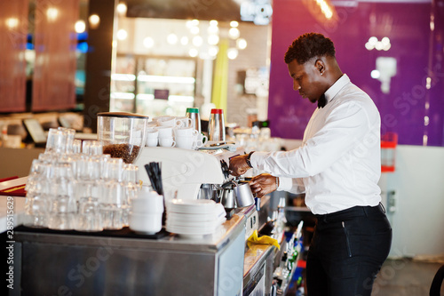Fototapeta Naklejka Na Ścianę i Meble -  African american bartender barista at bar preparing coffee.