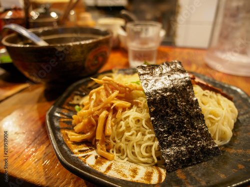 Wide closeup of Tsukemen ramen noodles, with bamboo sprouts. seaweed, and dipping sauce, on a restaurant counter. Nakano, Tokyo, Japan. Travel and cuisine. photo