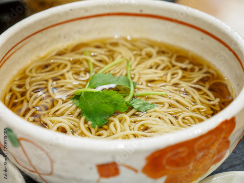 Closeup macro detail of hot Kake Soba, buckwheat noodles, served in a traditional ceramic bowl. Narita, Chiba, Japan. Travel and cuisine.