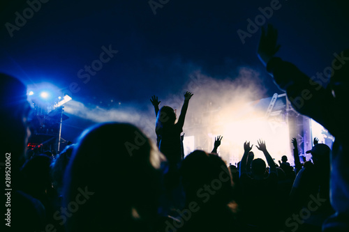 Fototapeta Naklejka Na Ścianę i Meble -  Silhouettes of raised hands on the concert in the night. Little girl with the hands up is sitting on the neck. The crowd of people at the open air music festival. Music background.
