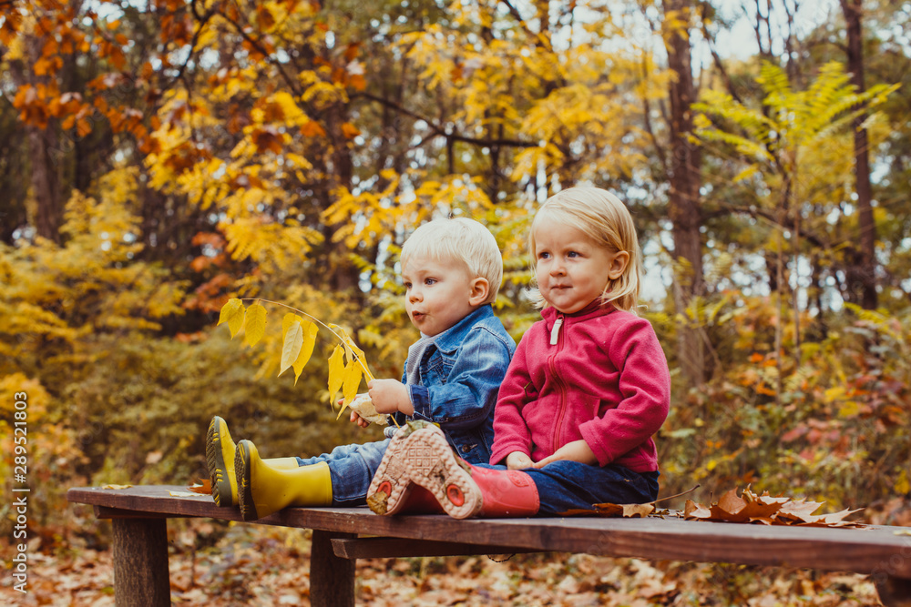 Two smiling happy kids friends, boy and girl sitting on the bench Two smiling happy kids friends, boy and girl sitting on the bench