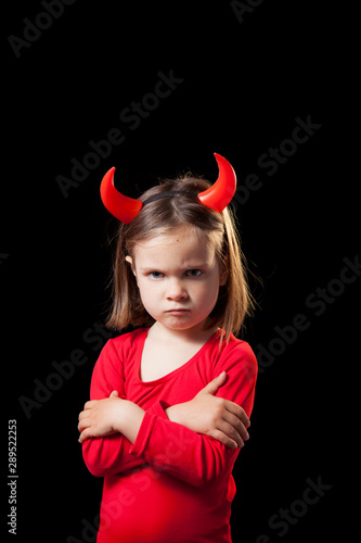 Studio shot of a Cute 5 years old girl with a red devil costume against black background